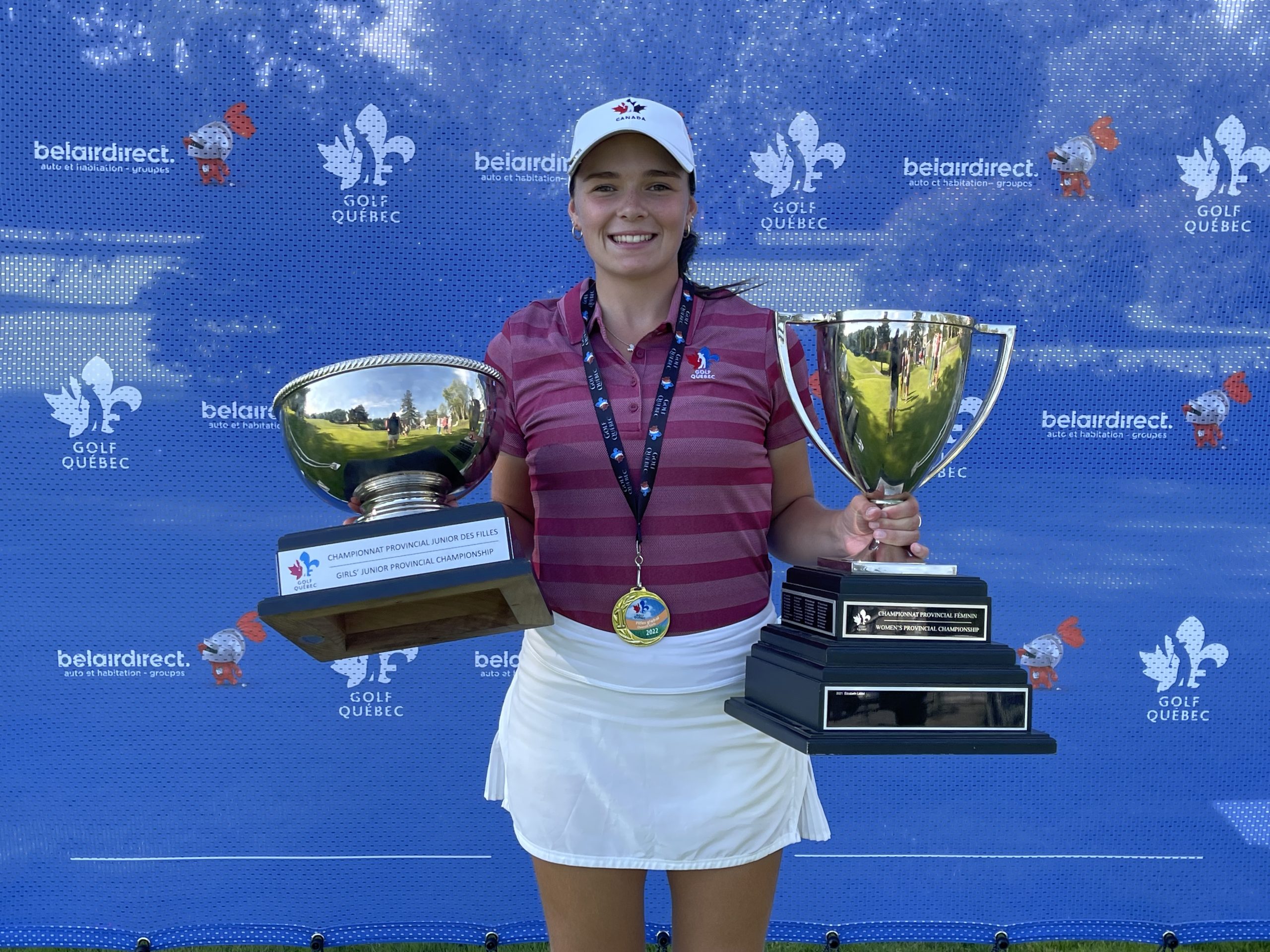 Une golfeuse souriante qui tient deux trophées.