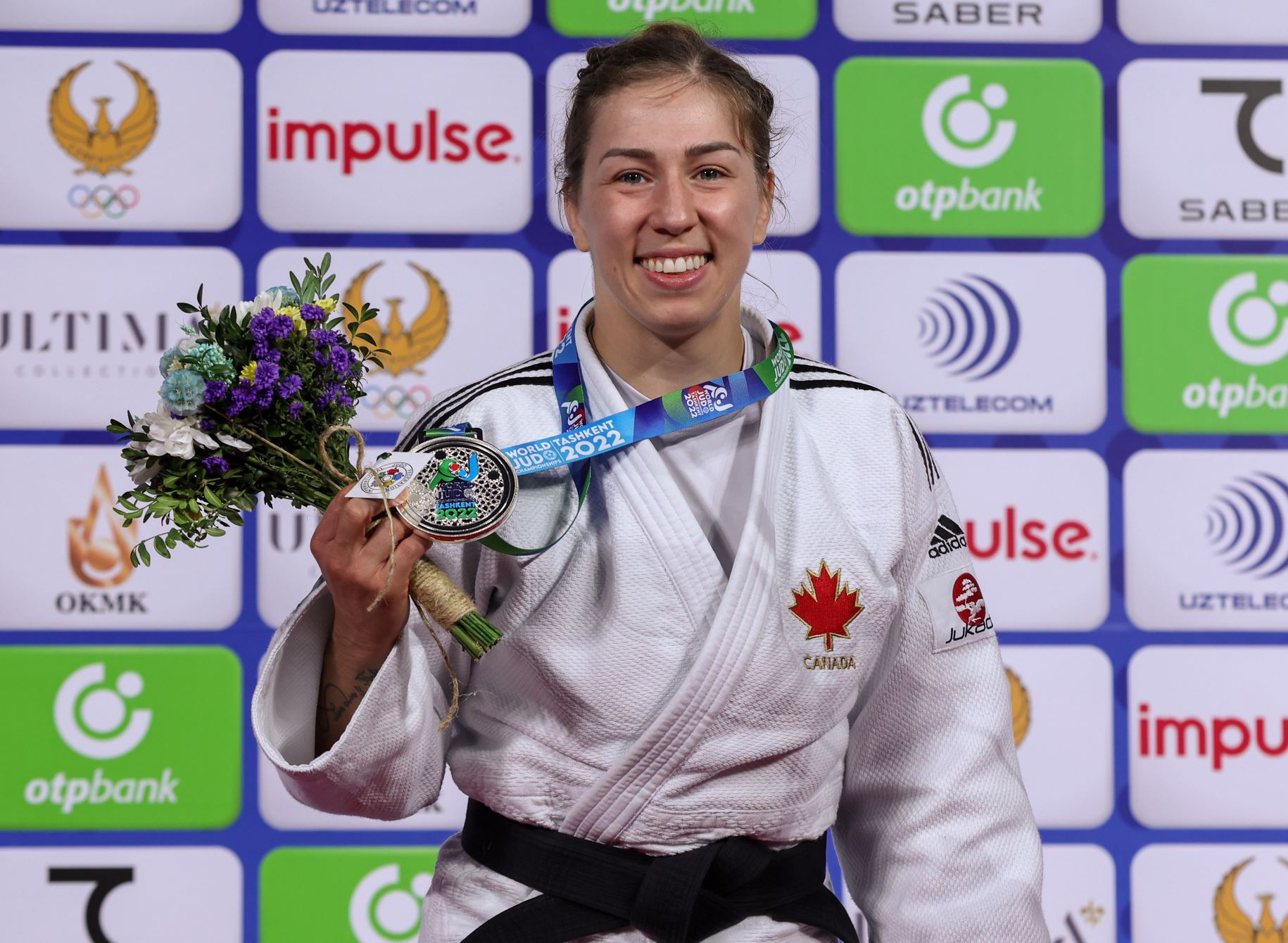 Une judoka souriante avec sa médaille.