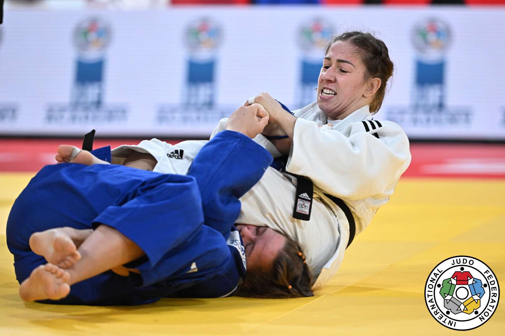Deux athlètes en judo combattent sur le tatami.