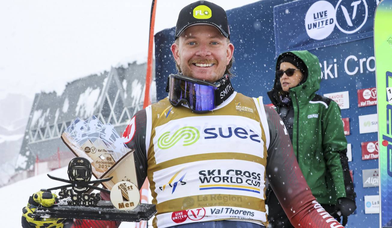 Un skieur canadien souriant avec sa médaille et son trophée.