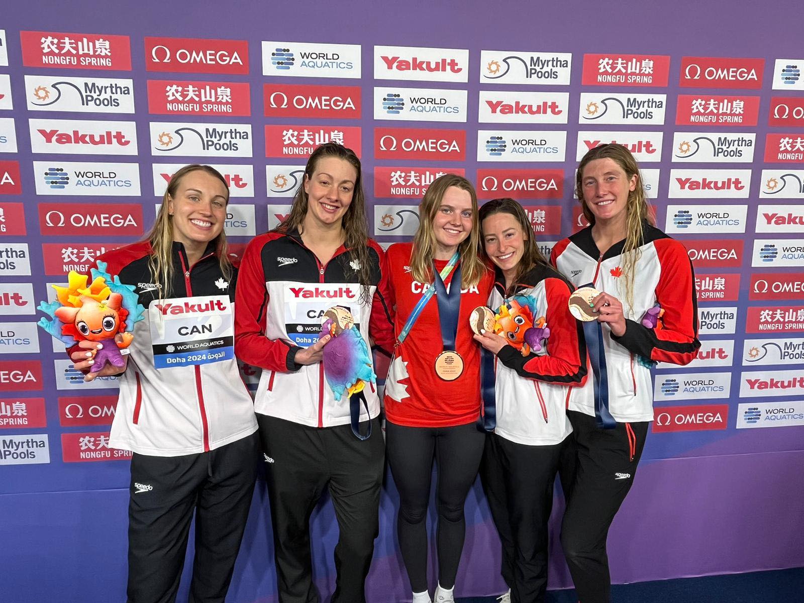 Cinq nageuses canadiennes souriantes avec leurs médailles.